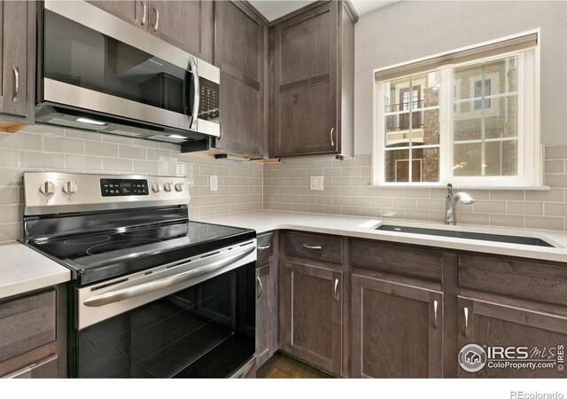 4902 Brookfield Dr Unit F, Fort Collins, CO 80528 - kitchen featuring appliances with stainless steel finishes, a sink, dark brown cabinets, and backsplash