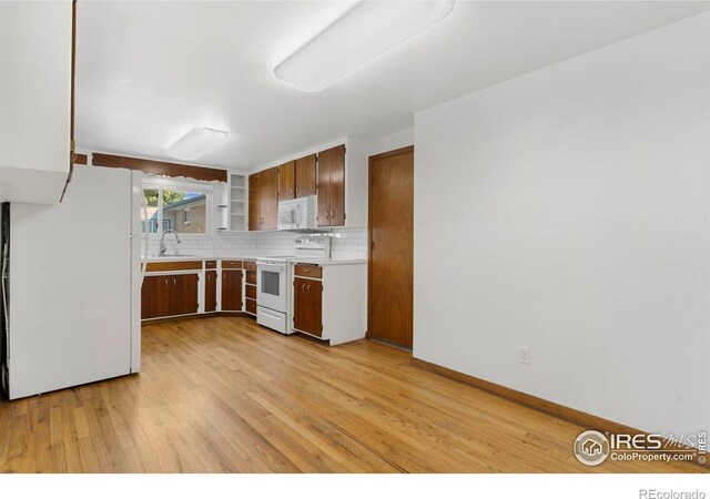 1229 Juniper St, Longmont, CO 80501 - kitchen featuring white appliances, a sink, light countertops, light wood finished floors, and tasteful backsplash
