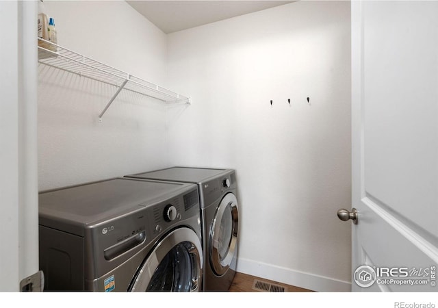 1566 Driftline Dr, Severance, CO 80550 - laundry area with washer and clothes dryer, baseboards, and wood finished floors