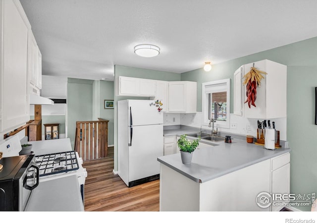 453 Black Fawn Ln, Westcliffe, CO 81252 - kitchen with white appliances, a sink, light wood-style flooring, white cabinets, and a peninsula