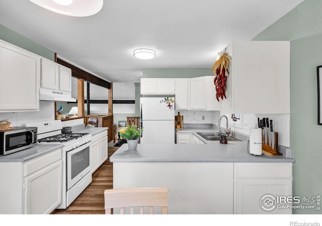 453 Black Fawn Ln, Westcliffe, CO 81252 - kitchen with white appliances, a sink, under cabinet range hood, a peninsula, and white cabinetry