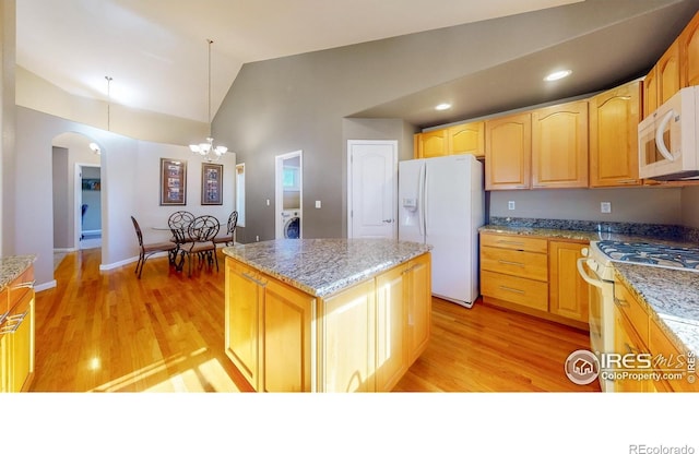 8211 Lighthouse Lane Ct, Windsor, CO 80528 - kitchen with white appliances, arched walkways, lofted ceiling, a center island, and washer / clothes dryer