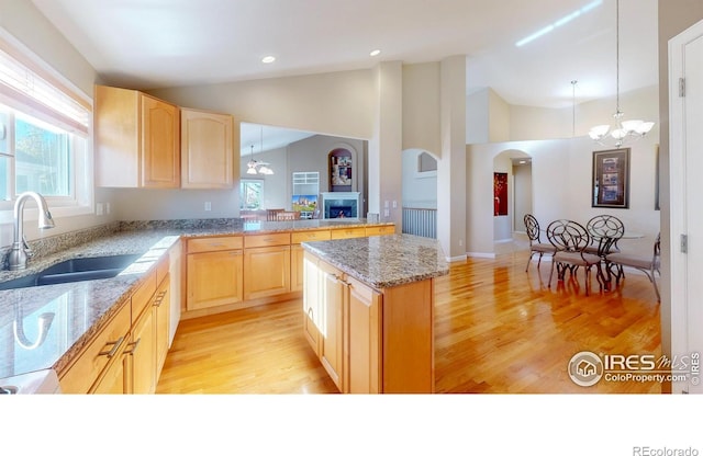 8211 Lighthouse Lane Ct, Windsor, CO 80528 - kitchen with light brown cabinets, a fireplace, healthy amount of natural light, light wood finished floors, and high vaulted ceiling