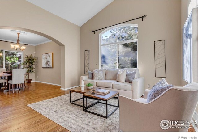2841 Silver Pl, Superior, CO 80027 - living room with a chandelier, wood finished floors, arched walkways, baseboards, and high vaulted ceiling