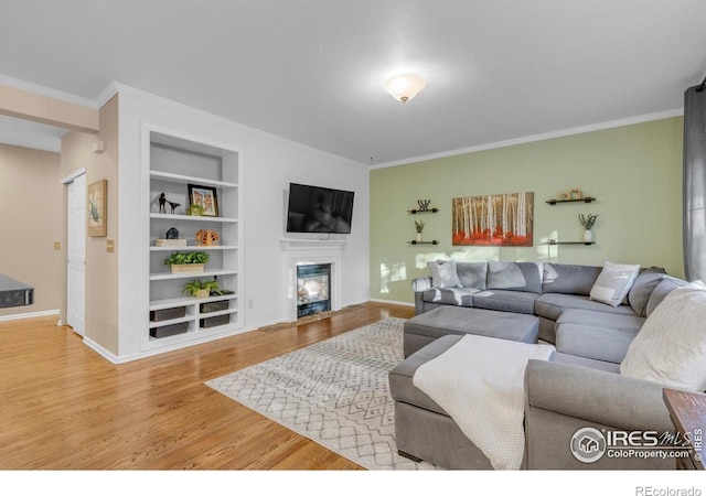2841 Silver Pl, Superior, CO 80027 - living room with built in features, wood finished floors, a glass covered fireplace, crown molding, and baseboards