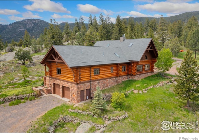 95 Choctaw Rd, Lyons, CO 80540 - view of front facade featuring log siding, a view of trees, an attached garage, a mountain view, and dirt driveway