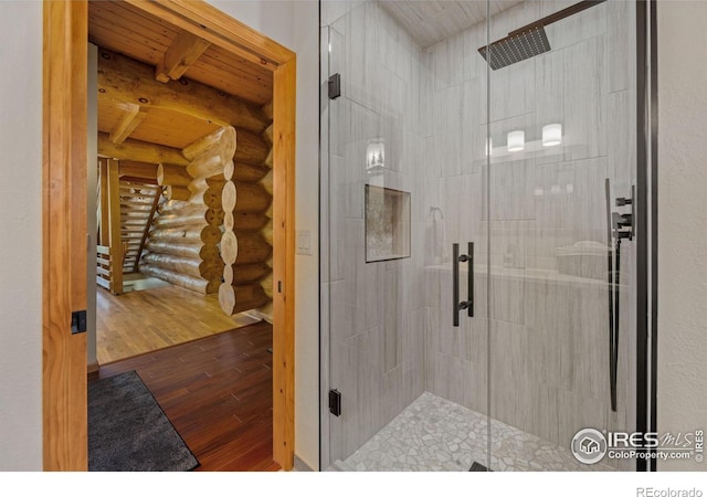 95 Choctaw Rd, Lyons, CO 80540 - full bath with rustic walls, hardwood / wood-style floors, a stall shower, and wood ceiling with exposed beams