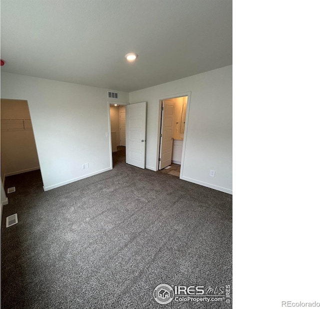 420 Condor Way, Johnstown, CO 80534 - unfurnished bedroom with baseboards, a spacious closet, dark colored carpet, and connected bathroom