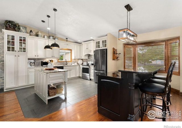 1738 S Estrella Ave, Loveland, CO 80537 - kitchen with appliances with stainless steel finishes, a center island, vaulted ceiling, custom exhaust hood, and tasteful backsplash