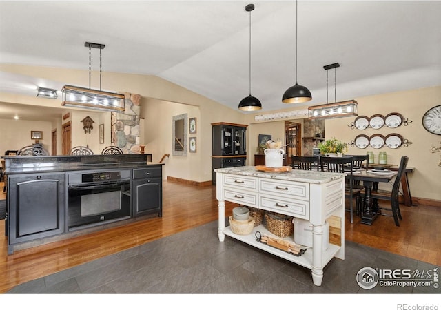 1738 S Estrella Ave, Loveland, CO 80537 - kitchen with oven, a center island, lofted ceiling, dark wood-style flooring, and baseboards
