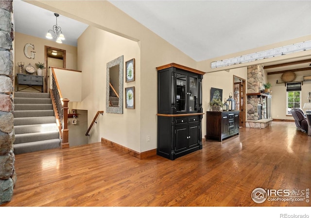 1738 S Estrella Ave, Loveland, CO 80537 - interior space with wood finished floors, stairs, a stone fireplace, a chandelier, and baseboards