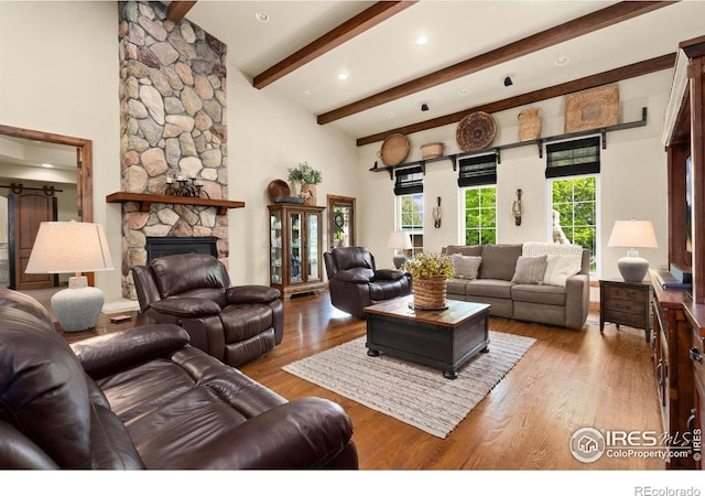 1738 S Estrella Ave, Loveland, CO 80537 - living area with wood finished floors, beamed ceiling, a stone fireplace, recessed lighting, and a towering ceiling