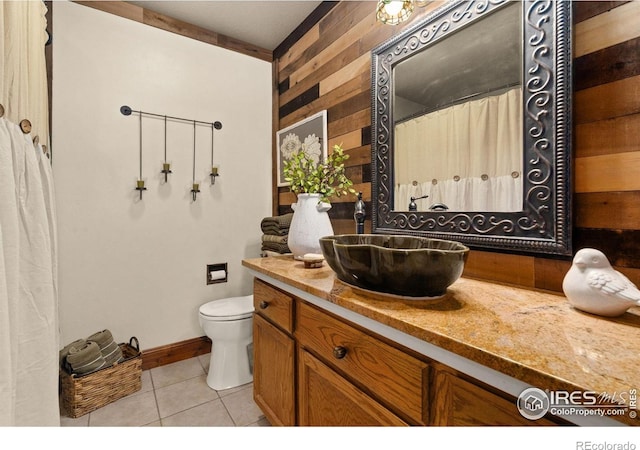 1738 S Estrella Ave, Loveland, CO 80537 - bathroom with toilet, tile patterned floors, vanity, wooden walls, and baseboards