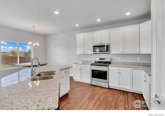 993 Ouzel Falls Rd, Severance, CO 80550 - kitchen with stainless steel appliances, a sink, wood finished floors, a chandelier, and white cabinetry