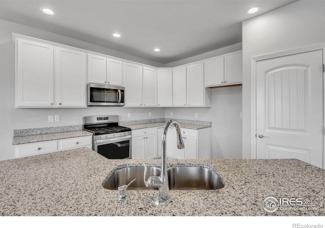 993 Ouzel Falls Rd, Severance, CO 80550 - kitchen featuring stainless steel appliances, a sink, white cabinetry, light stone counters, and recessed lighting