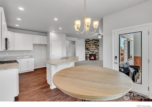993 Ouzel Falls Rd, Severance, CO 80550 - dining area with a fireplace, dark wood-type flooring, recessed lighting, a chandelier, and ceiling fan