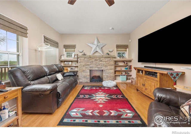 23462 County Road 55, Kersey, CO 80644 - living room featuring a ceiling fan, wood finished floors, and a stone fireplace