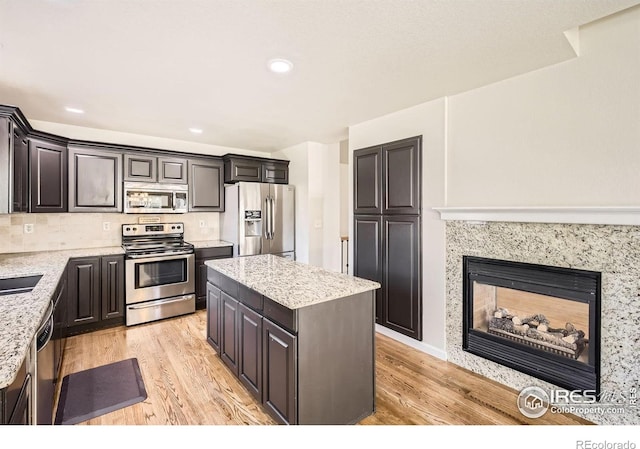 520 N Harding Ave, Johnstown, CO 80534 - kitchen with stainless steel appliances, light wood-style floors, light stone counters, a kitchen island, and recessed lighting