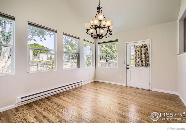 520 N Harding Ave, Johnstown, CO 80534 - unfurnished dining area with baseboard heating, a chandelier, plenty of natural light, and light wood-style flooring