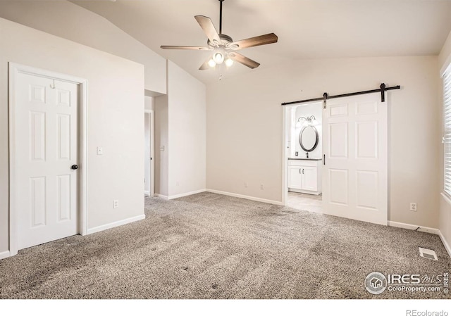 520 N Harding Ave, Johnstown, CO 80534 - unfurnished bedroom with vaulted ceiling, carpet flooring, a barn door, baseboards, and ensuite bath