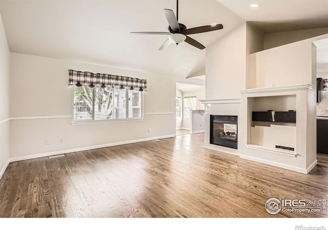 520 N Harding Ave, Johnstown, CO 80534 - unfurnished living room featuring a ceiling fan, wood finished floors, a multi sided fireplace, baseboards, and high vaulted ceiling