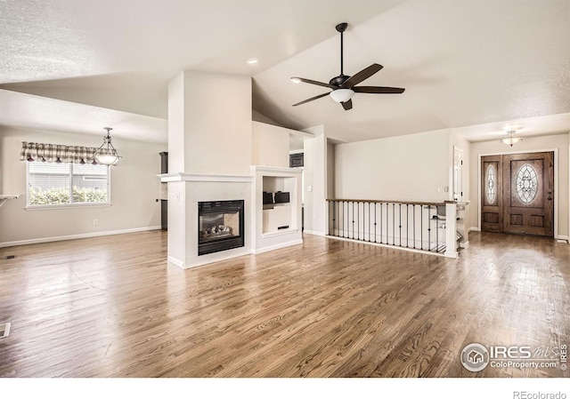 520 N Harding Ave, Johnstown, CO 80534 - unfurnished living room with ceiling fan, wood finished floors, vaulted ceiling, baseboards, and a multi sided fireplace