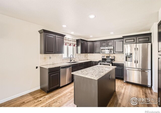 520 N Harding Ave, Johnstown, CO 80534 - kitchen with stainless steel appliances, a sink, backsplash, baseboards, and light wood-type flooring