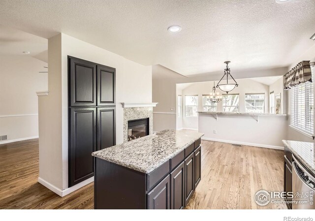 520 N Harding Ave, Johnstown, CO 80534 - kitchen with stainless steel dishwasher, light wood-style floors, a tile fireplace, light stone counters, and a textured ceiling