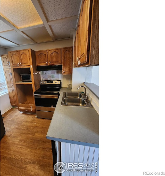 305 Phelps St, Sterling, CO 80751 - kitchen featuring stainless steel range with electric stovetop, under cabinet range hood, a sink, wood finished floors, and brown cabinets