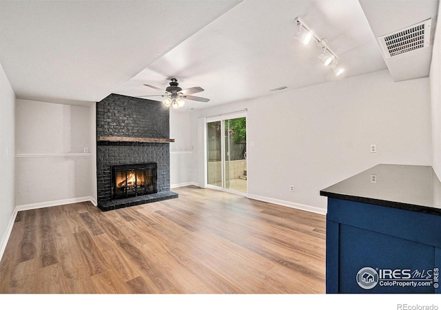 2824 Edinburgh Ct, Fort Collins, CO 80525 - unfurnished living room featuring ceiling fan, a fireplace, wood finished floors, baseboards, and rail lighting