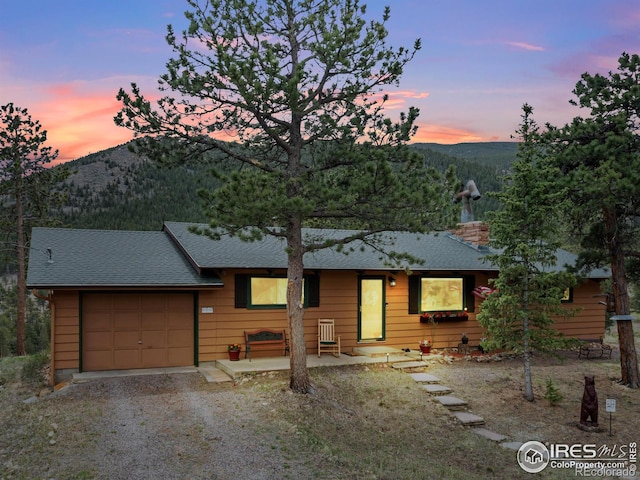 839 Ski Rd, Allenspark, CO 80510 - view of front of property featuring a mountain view, a garage, gravel driveway, a shingled roof, and a chimney