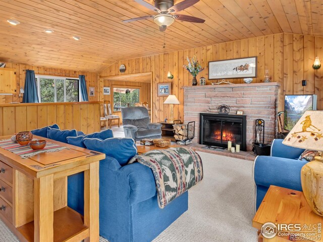 839 Ski Rd, Allenspark, CO 80510 - carpeted living room with lofted ceiling, wooden walls, ceiling fan, wooden ceiling, and a glass covered fireplace
