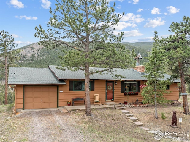 839 Ski Rd, Allenspark, CO 80510 - view of front of home featuring a mountain view, an attached garage, dirt driveway, a shingled roof, and a chimney