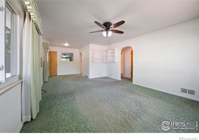 201 Howard St, Brush, CO 80723 - carpeted empty room with arched walkways, ceiling fan, and baseboards