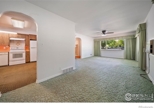 201 Howard St, Brush, CO 80723 - unfurnished living room featuring arched walkways, light carpet, ceiling fan, and baseboards