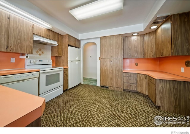 201 Howard St, Brush, CO 80723 - kitchen with white appliances, under cabinet range hood, arched walkways, light countertops, and recessed lighting