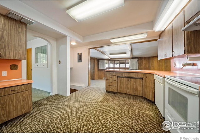 201 Howard St, Brush, CO 80723 - kitchen featuring white appliances, light countertops, carpet floors, arched walkways, and brown cabinetry