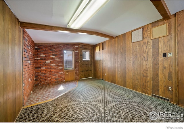 201 Howard St, Brush, CO 80723 - empty room with wood walls, beamed ceiling, and carpet floors