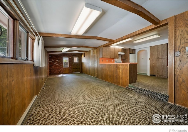 201 Howard St, Brush, CO 80723 - kitchen featuring wood walls, arched walkways, brown cabinets, a peninsula, and beamed ceiling