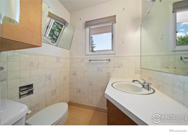 201 Howard St, Brush, CO 80723 - bathroom with tile walls, toilet, healthy amount of natural light, vanity, and wainscoting