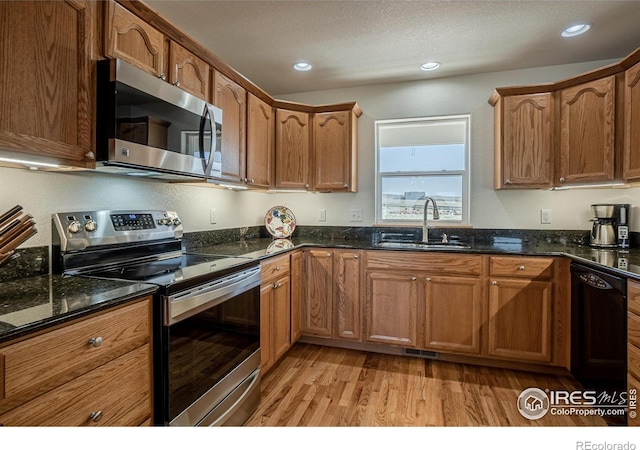 631 Linecamp Dr, Livermore, CO 80536 - kitchen with appliances with stainless steel finishes, a sink, light wood-style flooring, dark stone countertops, and recessed lighting