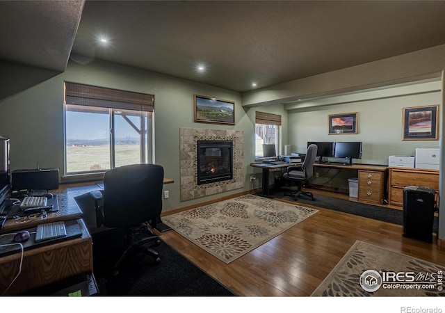 631 Linecamp Dr, Livermore, CO 80536 - office area featuring wood finished floors, a tile fireplace, healthy amount of natural light, baseboards, and recessed lighting