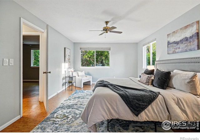 1359 Caledonia Cir, Louisville, CO 80027 - bedroom featuring multiple windows, baseboards, wood finished floors, and a ceiling fan