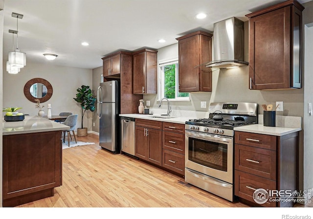 1359 Caledonia Cir, Louisville, CO 80027 - kitchen featuring appliances with stainless steel finishes, wall chimney exhaust hood, a sink, light wood-type flooring, and recessed lighting