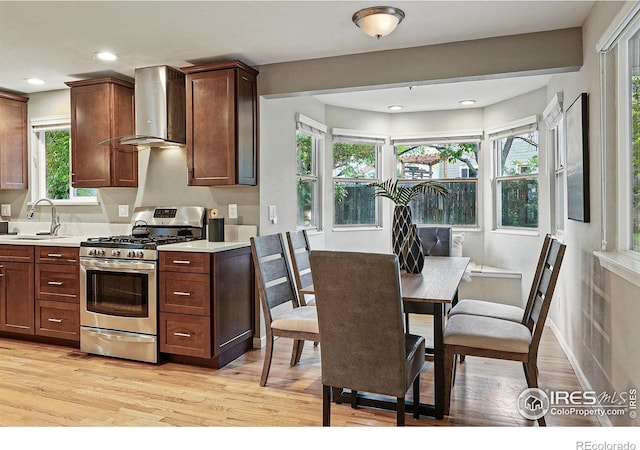 1359 Caledonia Cir, Louisville, CO 80027 - kitchen featuring wall chimney range hood, stainless steel range with gas cooktop, a sink, light countertops, and light wood-type flooring
