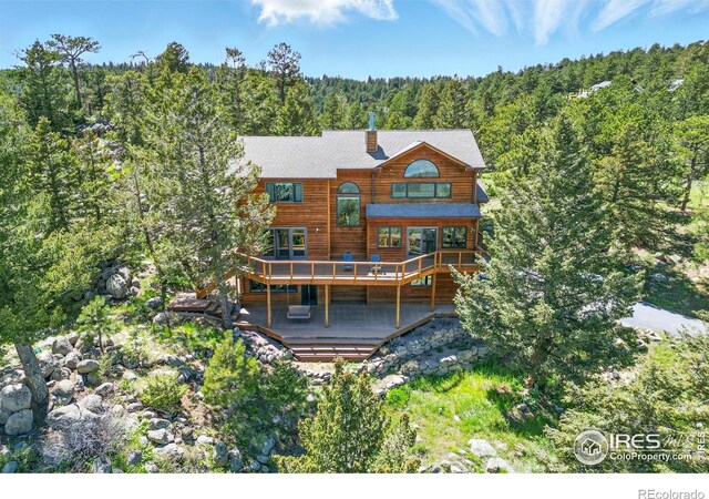 84 Canon View Rd, Boulder, CO 80302 - back of property featuring a wooded view, a wooden deck, and a chimney