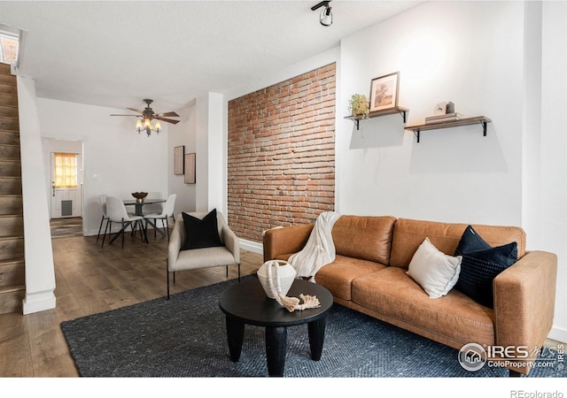 135 E 8th Ave, Denver, CO 80203 - living area featuring wood finished floors, ceiling fan, brick wall, and baseboards
