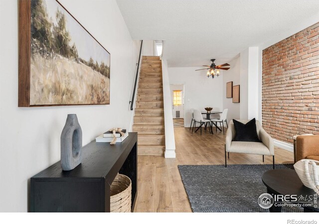 135 E 8th Ave, Denver, CO 80203 - living room featuring stairway, brick wall, light wood-style floors, a ceiling fan, and baseboards