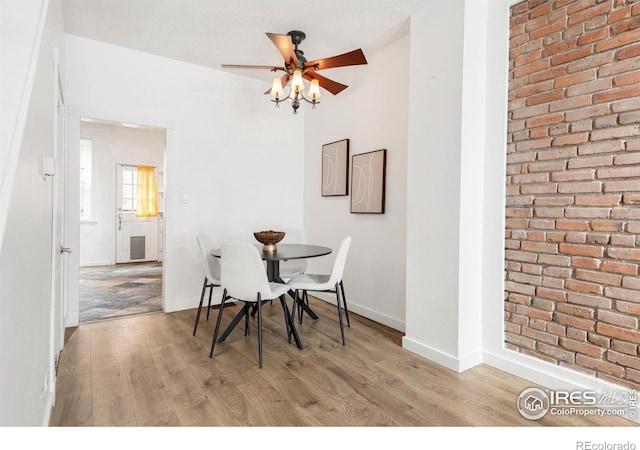 135 E 8th Ave, Denver, CO 80203 - dining room featuring light wood-type flooring, ceiling fan, baseboards, and brick wall