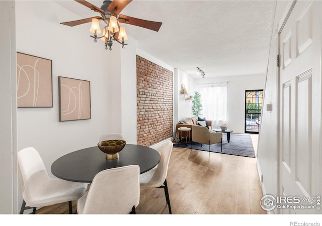135 E 8th Ave, Denver, CO 80203 - dining space featuring wood finished floors, a ceiling fan, brick wall, and a textured ceiling